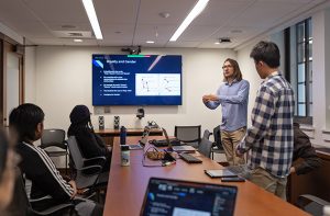 Meng Student Presentation in front of a tv screen